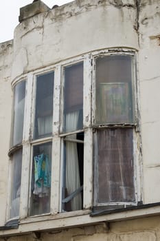 Neglected building with structural damage and broken window. View of squalid room.