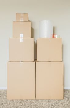 Variety of Packed Moving Boxes with Materials In Empty Room Against Wall.