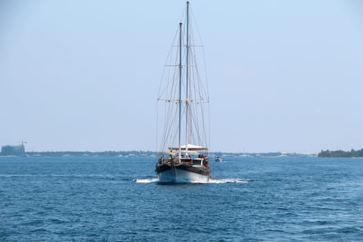 A nautical landscape with retro sailboat. Sea voyage on sailing yacht - luxury lifestyle in summer. Seashore with sailing vessel near islands, soft light effect.