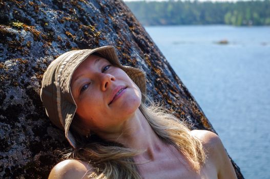 Young woman relax on a hill at the lake . Relax in the solitude of the watershore. with nature alone. Enjoying views of the lake landscape scale.