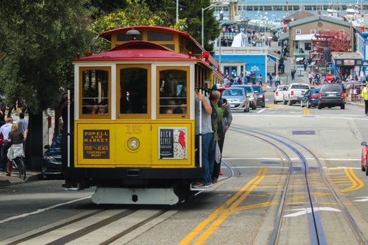 San Francisco, California - Mai 23, 2015: Tourists riding on the iconic cable car, blue sky day at top of Hyde Street view overlooking the bay water and Alcatraz prison