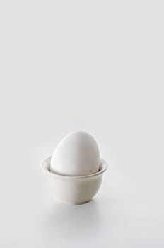 Egg in shell on stand, white background. High key, selective focus.