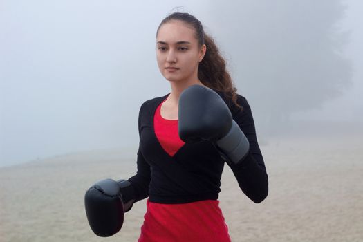 Young pretty slim fitness sporty woman does boxing exercises during training workout outdoor