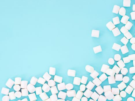 Marshmallows on blue background with copyspace. Flat lay or top view. Background or texture of colorful mini marshmallows.