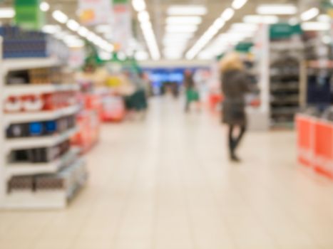 Abstract blurred supermarket aisle with colorful shelves and unrecognizable customers as background