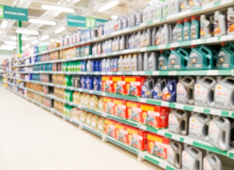 Blurred colorful motor oil bottles on shelves in supermarket as background
