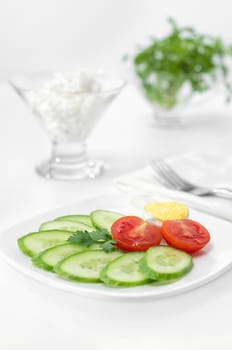 Sliced tomato, cucumber and half of the eggs onto a plate for Breakfast. A high key white background and selective focus.