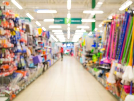 Abstract blurred supermarket aisle with colorful household goods shelves and unrecognizable customers as background