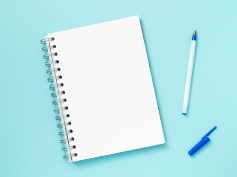 Top view of blank note paper with pen on blue wood table for background