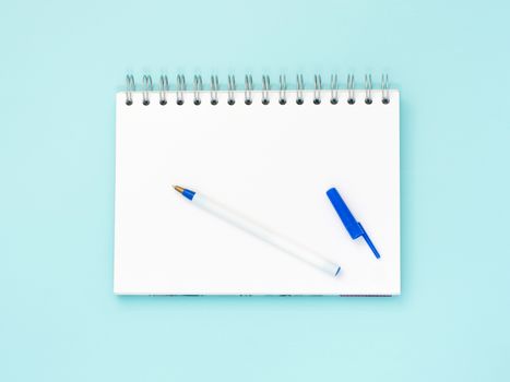 Top view of blank note paper with pen on blue wood table for background