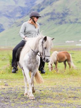 Woman riding a horse on the green field