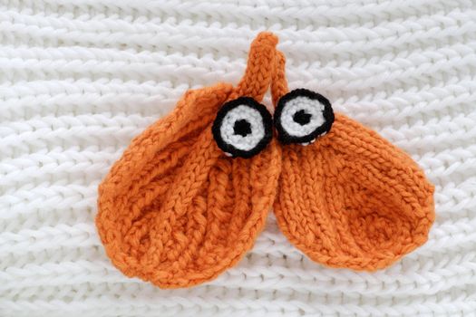 Humor eyes of winter make from yarn, diy simple background for Xmas holiday by knitted leaf for eyebrow, nose on white scarf background, joyful craft with funny face