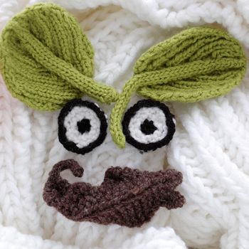 Humor eyes of winter make from yarn, diy simple background for Xmas holiday by knitted leaf for eyebrow, nose on white scarf background, joyful craft with funny face