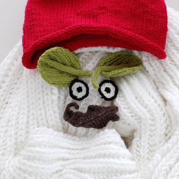 Humor eyes of winter make from yarn, diy simple background for Xmas holiday by knitted leaf for eyebrow, nose on white scarf background, joyful craft with funny face