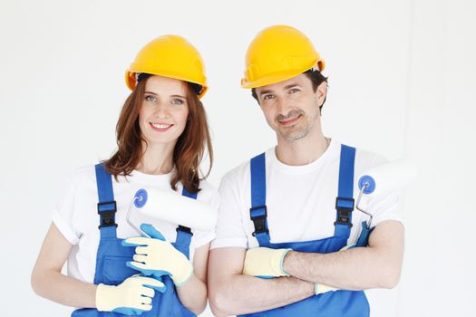 Happy couple in uniform holding paint rollers ready to work