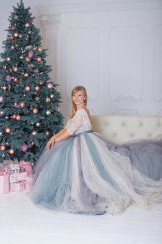 Blonde girl in evening dress sitting on a sofa in the new year eve