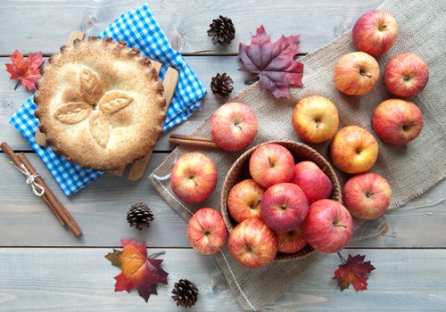 Apple pie with ingredients, cinammon sticks and autumn leaves