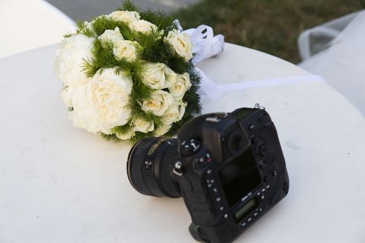 Close up view of a camera with a wedding bouquet in the background