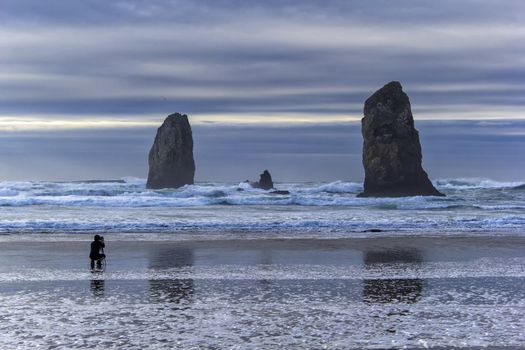 Photographer capturing waves by Haystack Rock at Cannon Beach along the Oregon Coast