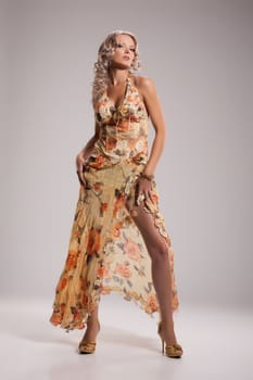 Young beautiful woman in a fashionable dress on a studio background