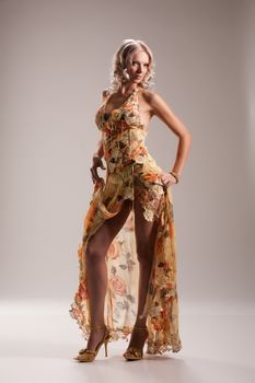 Young beautiful woman in a fashionable dress on a studio background