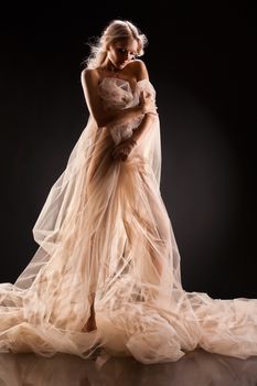 Young beautiful woman in a fashionable dress on a studio background
