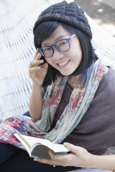asian woman and pocket book in hand relaxing on home cradle