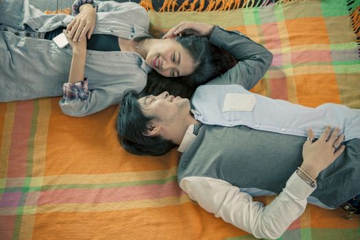 couples of younger asian man and woman relaxing emotion lying in home living room 