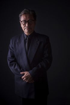 thai senior man wearing black suit sadness emotion ,portrait by low light photography