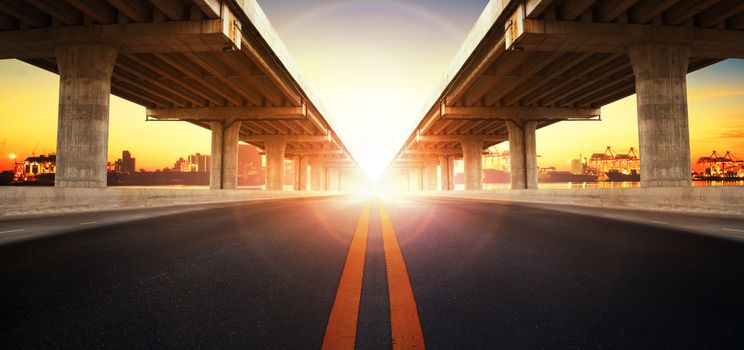 sun rising behind perspective on bridge ram construction and asphalt raod perspective to ship port background use for infra land and vessel transportation