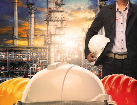 engineering man with white safety helmet standing in front of oil refinery building structure in heavy petrochemical industry 