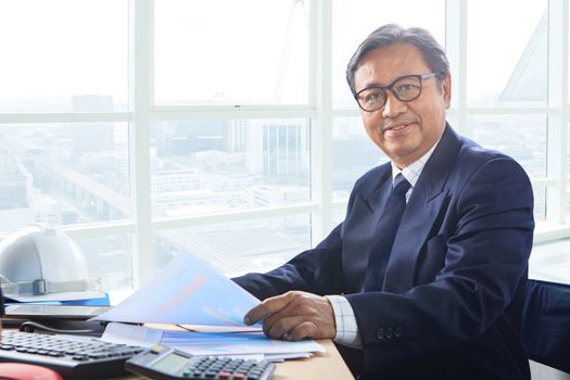 senior business man working on office table with smiling face happiness emotion