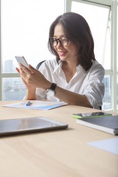 working woman reading message on smart phone with happiness emotion shot on office working table