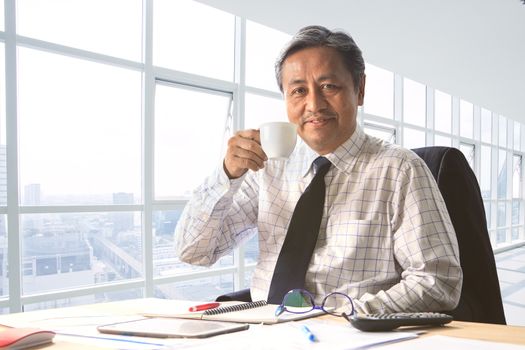 senior working man relaxing with drinking beverage in office room smiling face happiness emotion