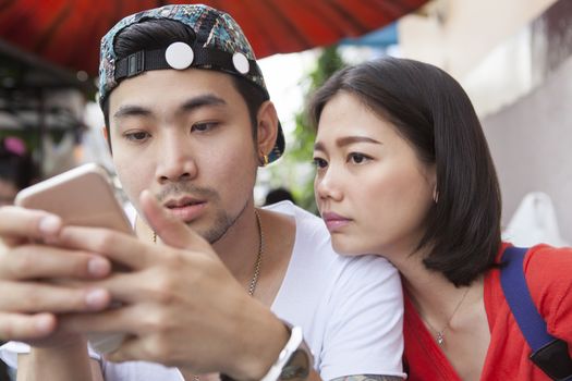 asian younger man and woman watching on smart phone use for people and digital technology ,wifi and internet connection 