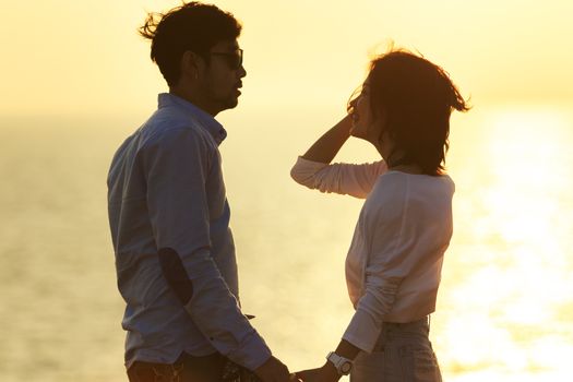 silhouette photography portrait of asian younger man and woman relaxing vacation at sea side happiness emotion against beautiful light of sun set sky