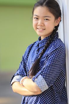 portrait of thai 12s years girl wearing blue shirt standing out door with toothy smiling face happiness emotion