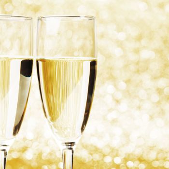 Pair of champagne flutes on shiny glitter background