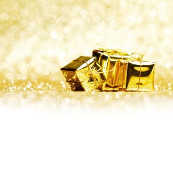 Small decorative golden presents on glitter background