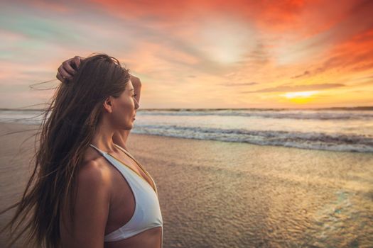 Beautiful sexy woman in bikini posing on beach at sunset