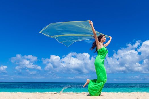 Young beautiful woman in dress run on beach holding fabric