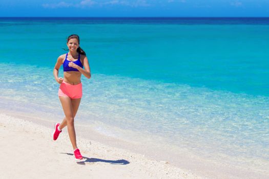 Beautiful young fitness woman running on beach