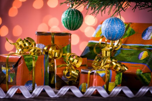 Christmas gifts with blurred lights and ribbon under the tree