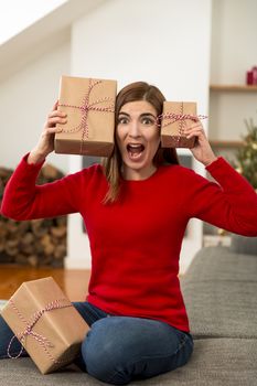 Beautiful woman at home in panic holding Christmas presents over her head