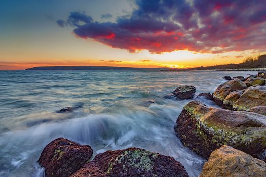 Exciting autumn sunset. Beauty sea rocky coast with slow shutter and waves flowing out.Varna, Bulgaria