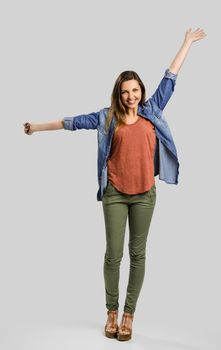 Beautiful happy woman with arms up over a gray background