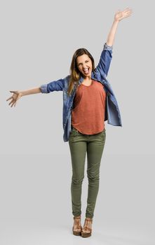 Beautiful happy woman with arms up over a gray background