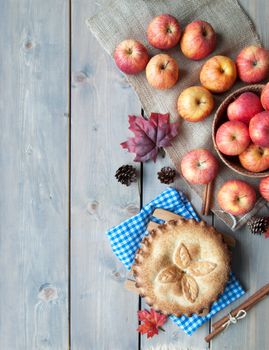 Apple pie with fruit ingredients and cinammon sticks on a wooden table