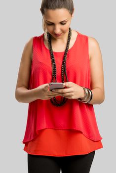 Beautiful woman texting a sms, isolated over gray background