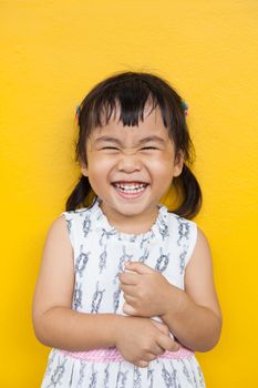 close up face of asian kid toothy smiling facial face with happiness emotion on yellow wall use for children lovely emotion and dental health theme